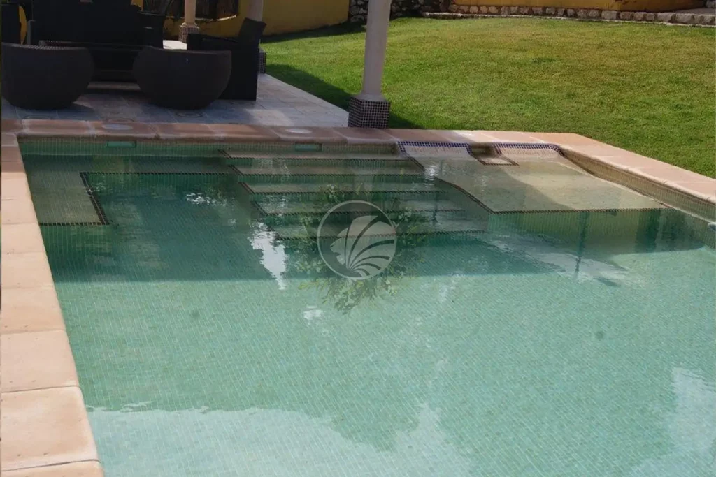 Escalera de una piscina con gresite marron en los bordes para remarcar